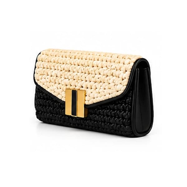 Ivory and black two-tone crochet Dar Al Ghazal envelope clutch from the front right, with the warm gold clasp on the ivory flap and the black leather gusset curving away at the side